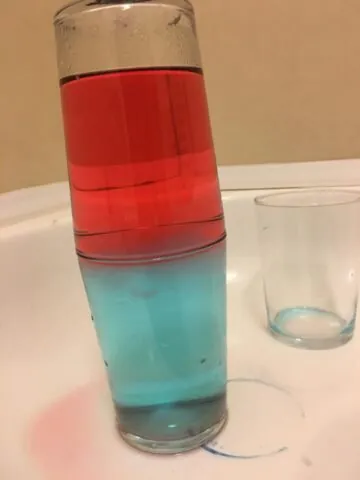 Două pahare suprapuse, cu apă colorată în roșu și albastru
