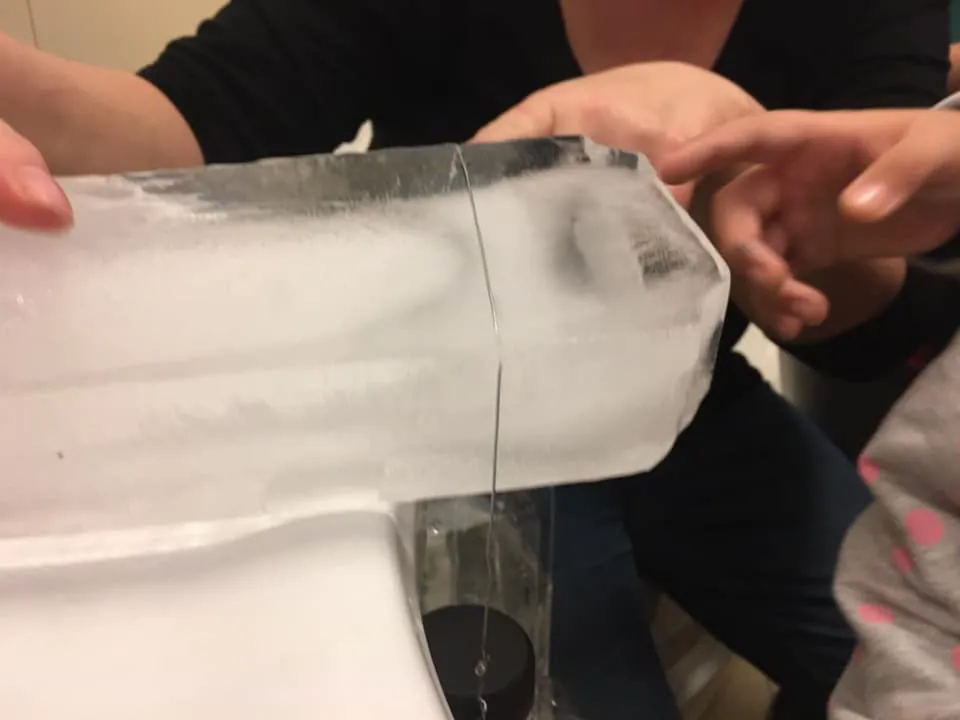 Bloc de gheață ținut în mâini, cu o sfoară prinsă de el