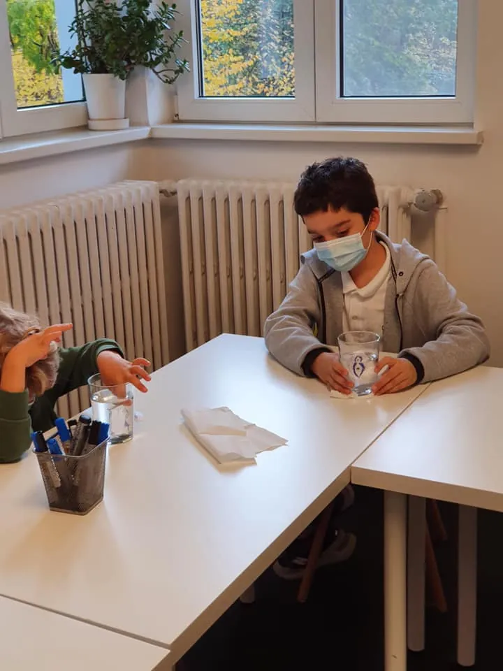 Băiat care urmărește un experiment cu un pahar de apă