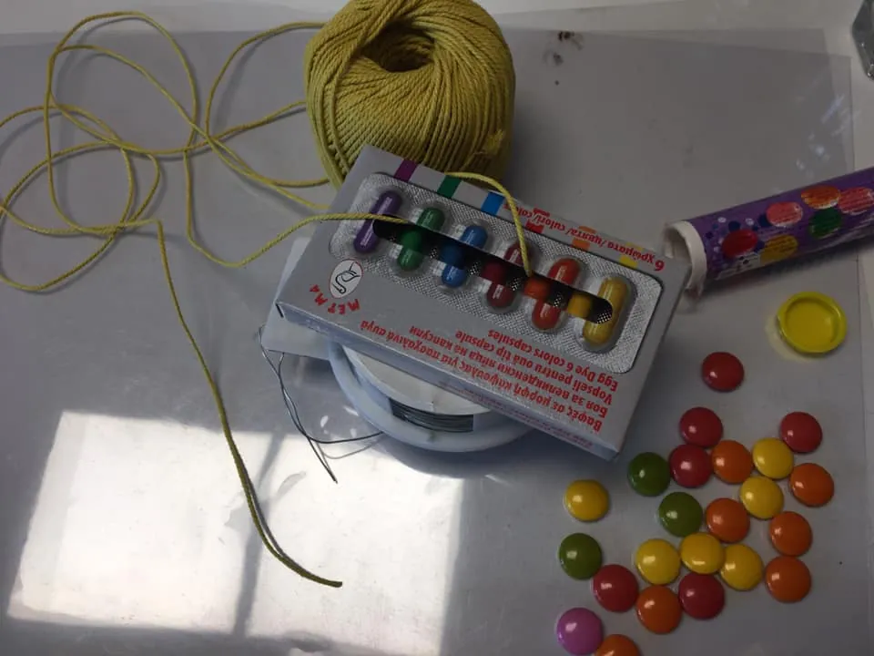 Bomboane colorate, o sfoară și o cutie de acuarele pregătite pentru un experiment